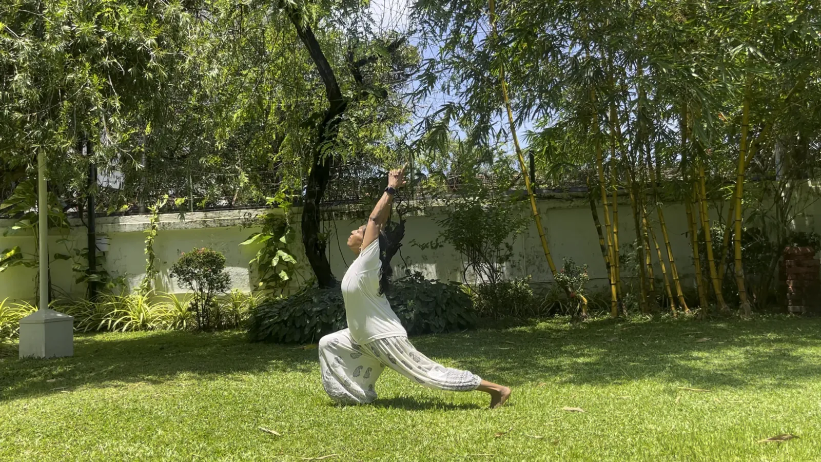 Yoga practitioner in a crescent lunge (Anjaneyasana) on a sunlit garden lawn